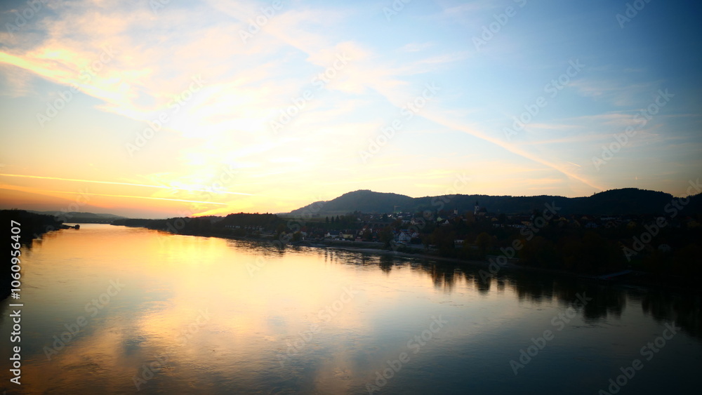 Fototapeta premium oranger Himmel spiegelt sich in der Donau, Abenddämmerung über Melk