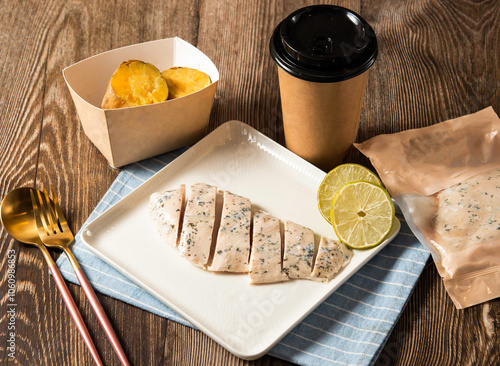 Lemon Grilled Chicken breast Meal served in plate with roasted sweet potatoes, disposable cup of coffee and fork isolated on napkin side view of taiwan food on table photo