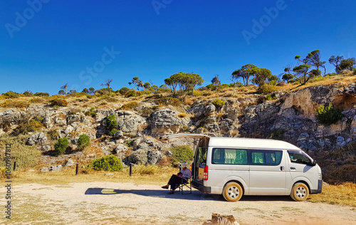 Senior man camping with a small motor home in front of a cliff at the Western Australian coast. Camping ground Cliff Head, south of Dongara, on the Indian Ocean Drive
 photo