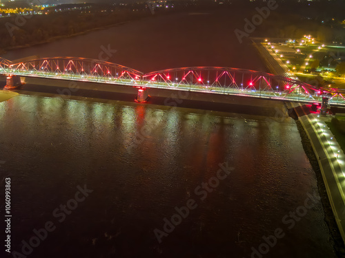 Aerial view of the illuminated bridge in Torun, Poland, at night, seen from the Vistula River.