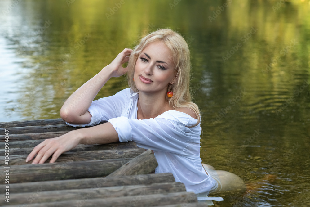 Portrait of a young beautiful blonde girl in a white shirt near the river. Portrait of a young beautiful blonde girl in a white shirt near the river.