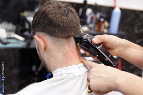 Men's haircutting with hair clipper in a barber shop or hair salon. Hairdresser service in a barbershop.