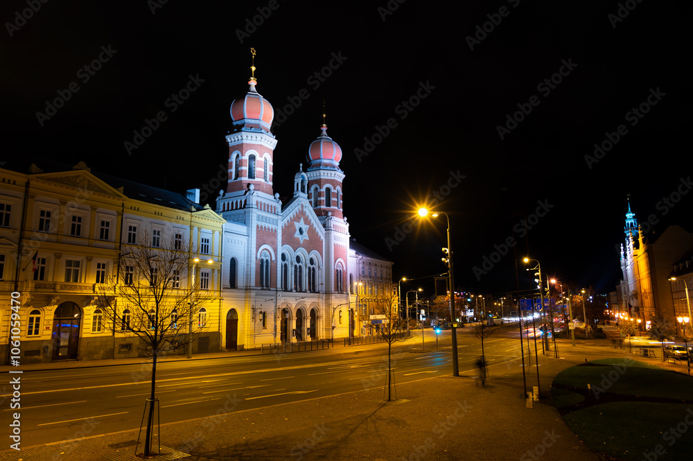 A captivating night view of the illuminated synagogue in Pilsen, showcasing its stunning architecture and warm lights, creating a serene and magical atmosphere
