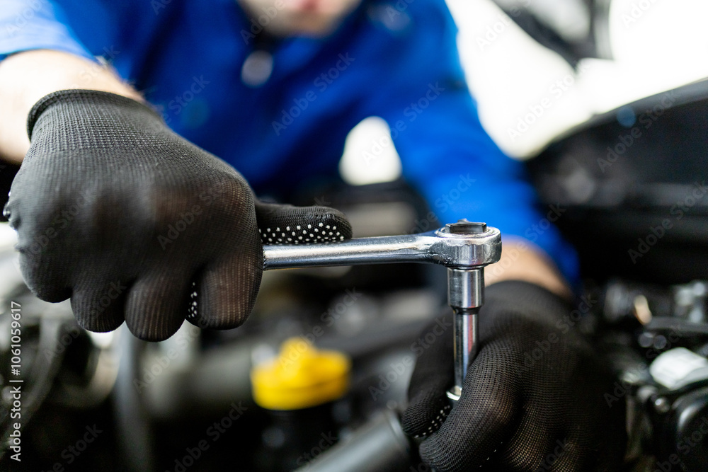 © zphoto83 - Auto mechanic working on an engine with a ratchet tool in a workshop, focusing on repairs during the day