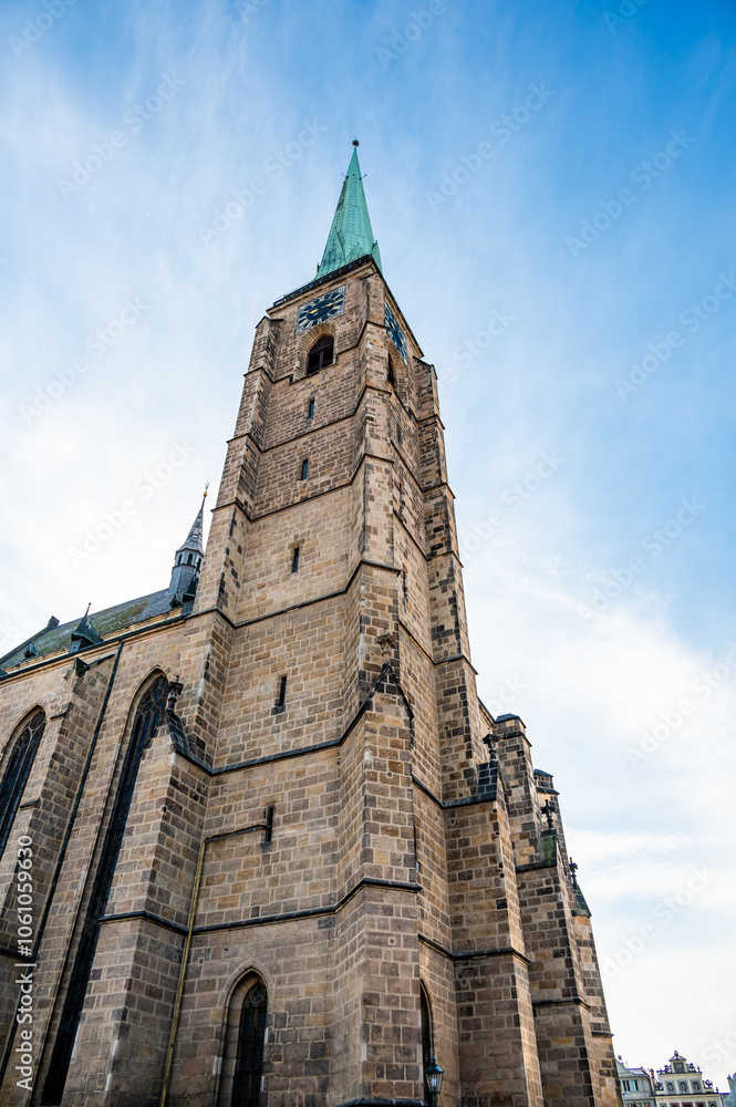 A photograph of the Cathedral of St. Bartholomew in Plzen, Czech Republic. This Gothic cathedral with its iconic tower stands proudly, surrounded by historic buildings, offering a stunning view