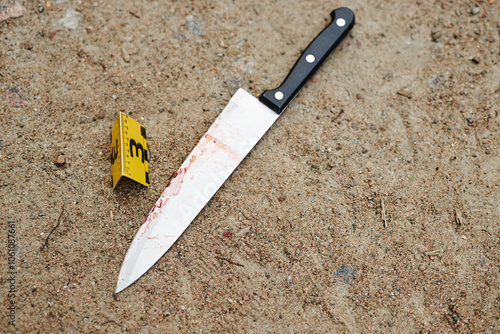 Foto Top view of knife with red traces at crime scene as evidence tagged by number, c