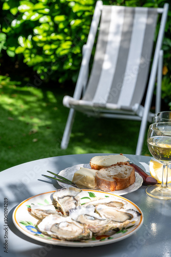 Plate with fresh live oysters with citron, bread, butter and white wine served at restaurant in oyster-farming village, Arcachon bay, Gujan-Mestras port, France