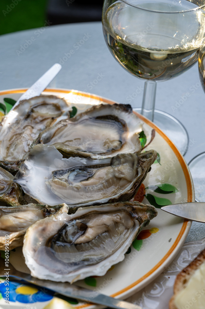 Plate with fresh live oysters with citron, bread, butter and white wine served at restaurant in oyster-farming village, Arcachon bay, Gujan-Mestras port, France Plate with fresh live oysters with citron, bread, butter and white wine served at restaurant in oyster-farming village, Arcachon bay, Gujan-Mestras port, France
