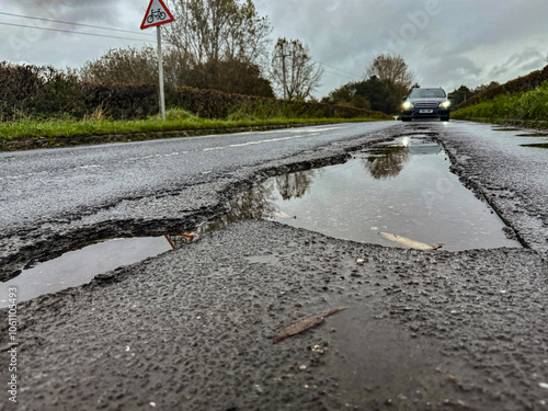 Rain-filled potholes on a rural road in the UK.   photo