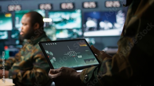 Army telecommunication systems operator using satellite software on tablet, providing combat support. Military dispatcher managing communications networks, with portable device, camera B photo