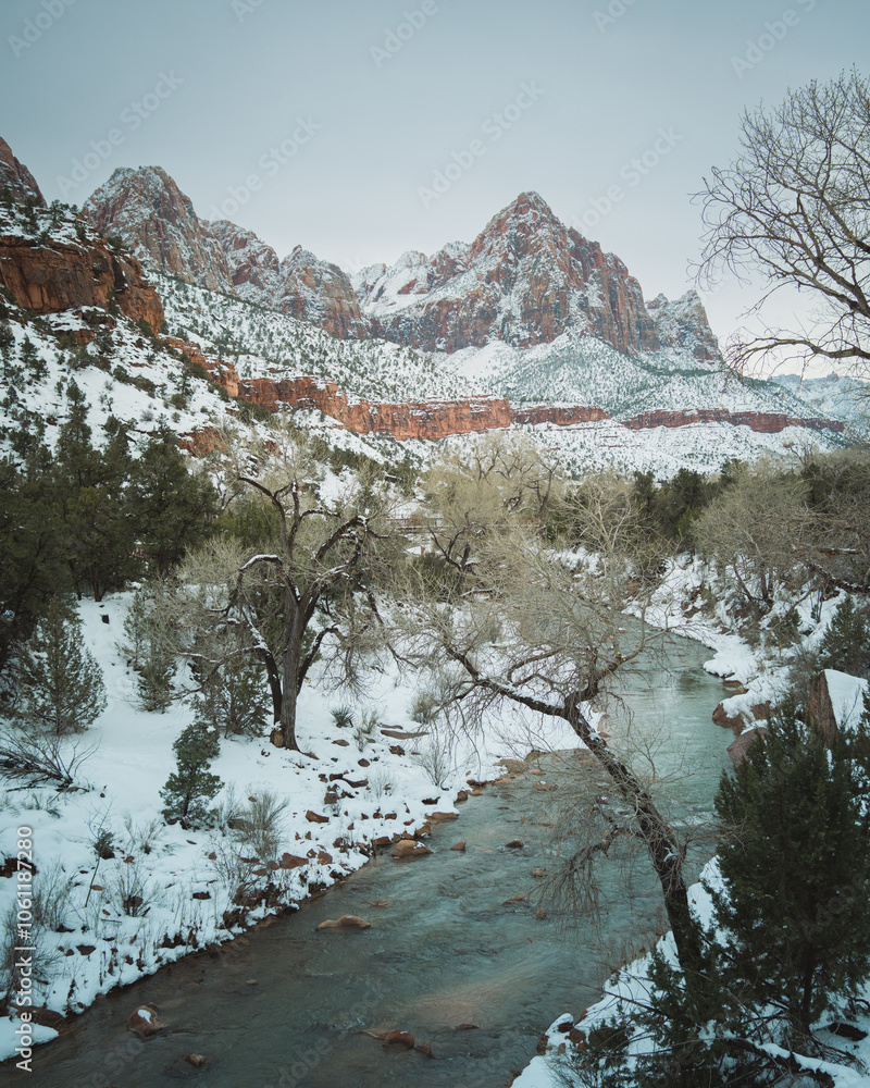 A snowy landscape features a winding river and towering cliffs at Zion National Park, Utah.
