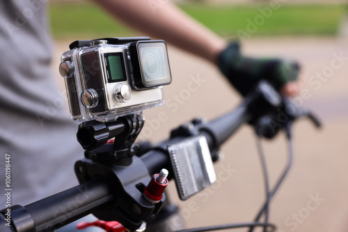 Man riding bicycle with modern action camera outdoors, closeup