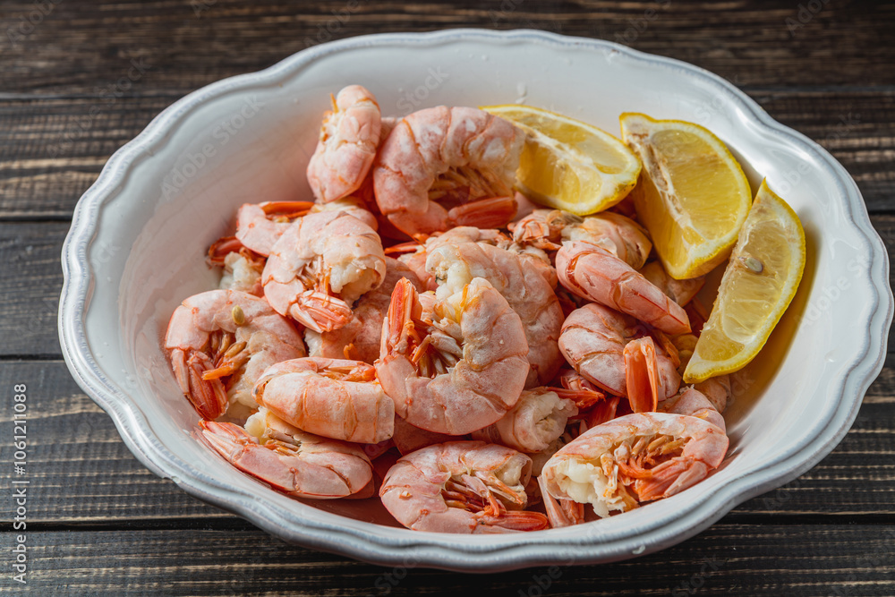 Boiled king prawns in deep bowl with lemon close up view on dark table Boiled king prawns in deep bowl with lemon close up view on dark table