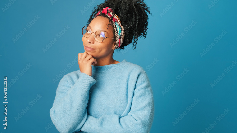 Young woman thinks, makes choice, makes decision, on blue background in studio Young woman thinks, makes choice, makes decision, on blue background in studio