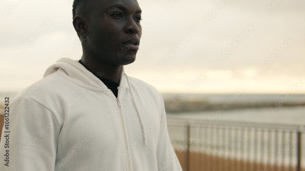 Young motivated man practicing outdoors to keep fit, catching his breath after an intense workout by the sea Young motivated man practicing outdoors to keep fit, catching his breath after an intense workout by the sea