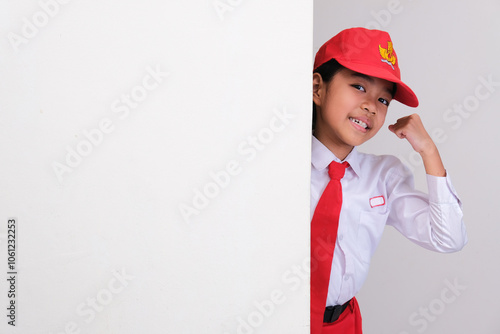 Indonesian school student peeking from behind a wall showing happy and excited expression photo