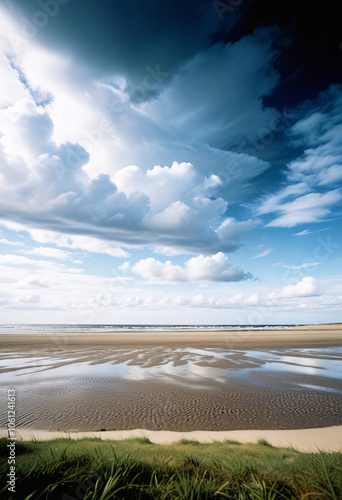 Vast sandy beach with a dramatic cloudy sky above, creating an expansive and serene landscape