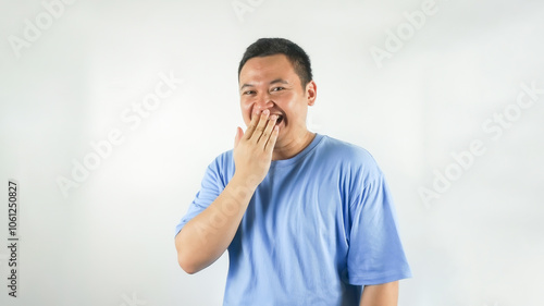 A young Indonesian man wearing a blue t-shirt is laughing facing forward