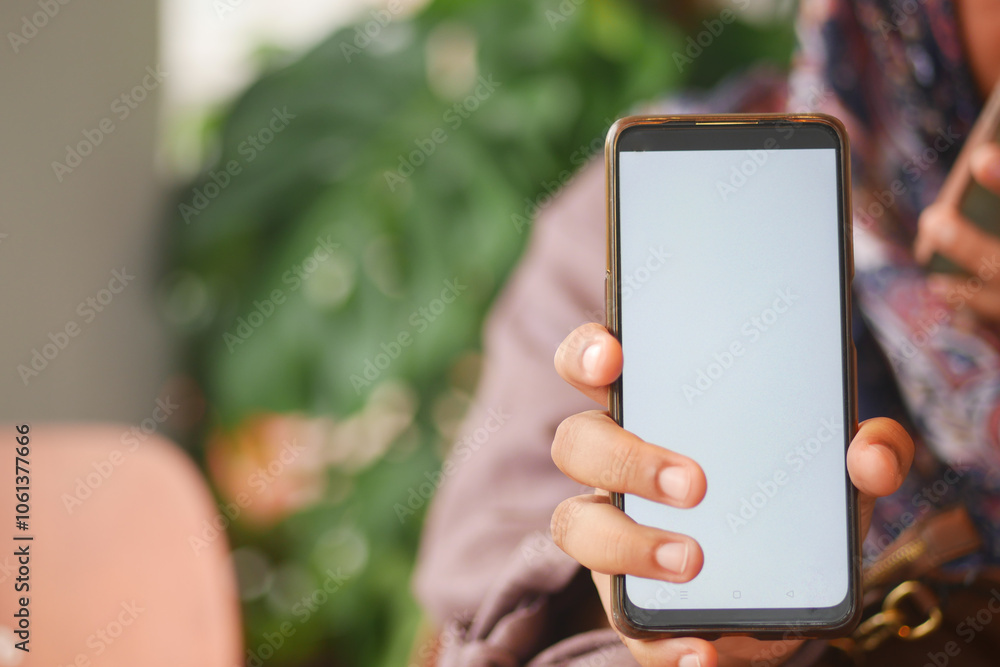 A Person Holding a Smartphone with a Blank Screen in a Cozy and Comfortable Setting A Person Holding a Smartphone with a Blank Screen in a Cozy and Comfortable Setting