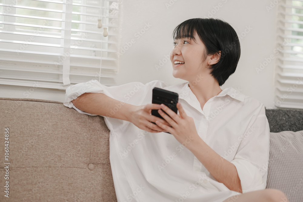 Young woman enjoys relaxing moment while browsing her phone on a cozy couch at home Young woman enjoys relaxing moment while browsing her phone on a cozy couch at home