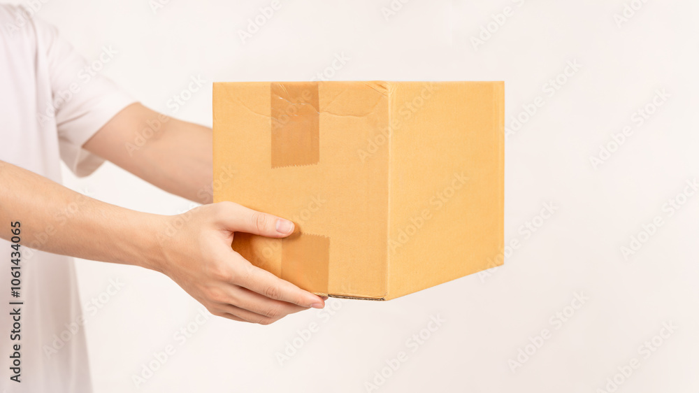 Hand holding cardboard box on empty background. Concept for transportation, online shopping, celebration and gift giving on special day. Hand holding cardboard box on empty background. Concept for transportation, online shopping, celebration and gift giving on special day.