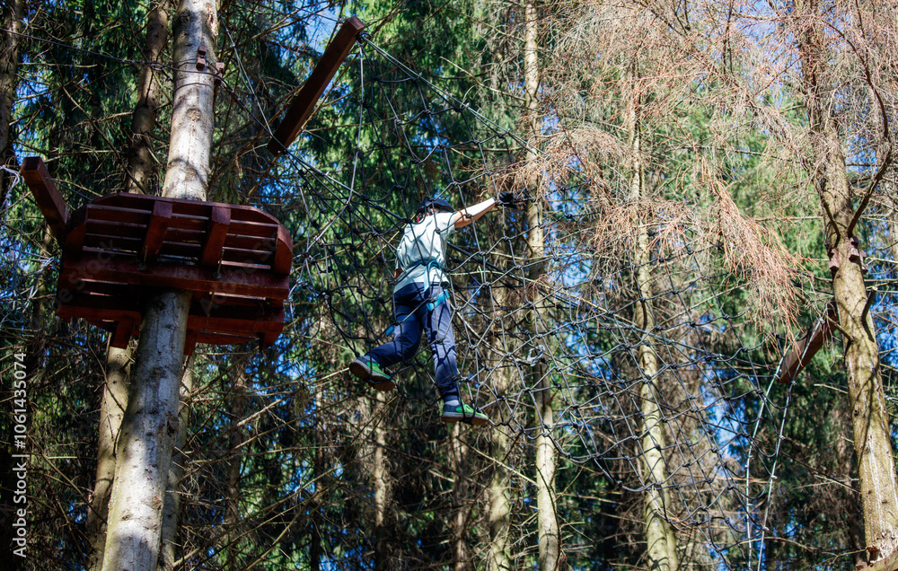 Fototapeta premium A man is jumping over a tree trunk on a rope course