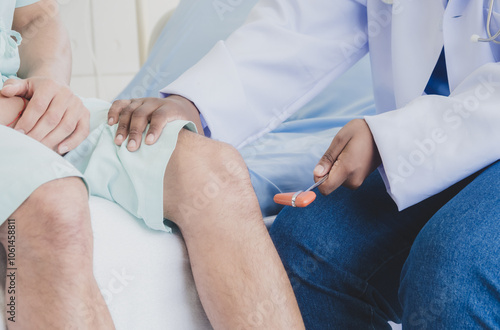 Closeup hand physical therapist woman doctor nurse African-American sitting holding cheack leg patient injury caucasian man two people talk helping support give advice inside treatment room hospital