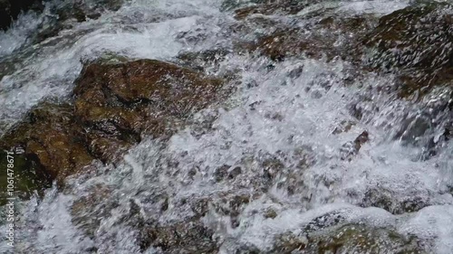 Rapid water stream flowing from cascade through the rocks under sunlight. Freshness clear water background.
