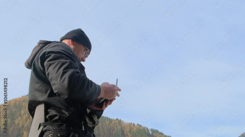 Close-up of a traveler man holding a drone controller in his hands with a blue sky and mountains on the background. Focused adult man controlling quadcopter. Close-up of a traveler man holding a drone controller in his hands with a blue sky and mountains on the background. Focused adult man controlling quadcopter.
