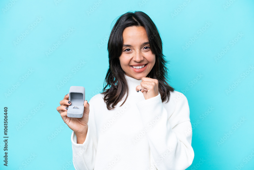 Young hispanic woman holding a engagement ring isolated on blue background proud and self-satisfied Young hispanic woman holding a engagement ring isolated on blue background proud and self-satisfied