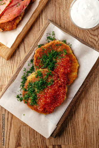 potato pancakes with red caviar on a wooden plate photo