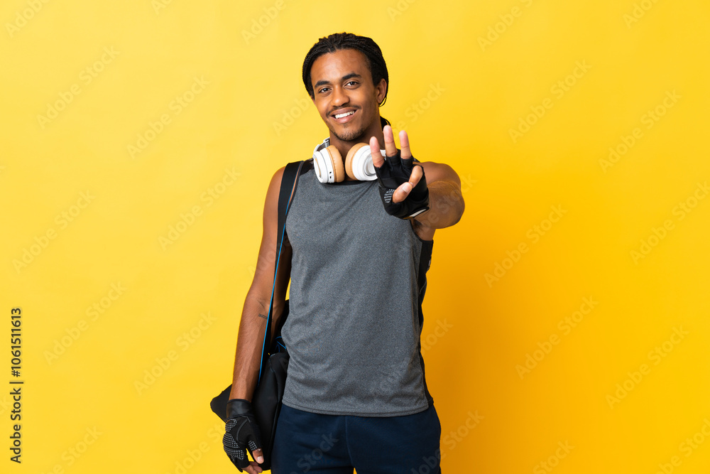 Young sport African American man with braids with bag isolated on yellow background happy and counting three with fingers Young sport African American man with braids with bag isolated on yellow background happy and counting three with fingers