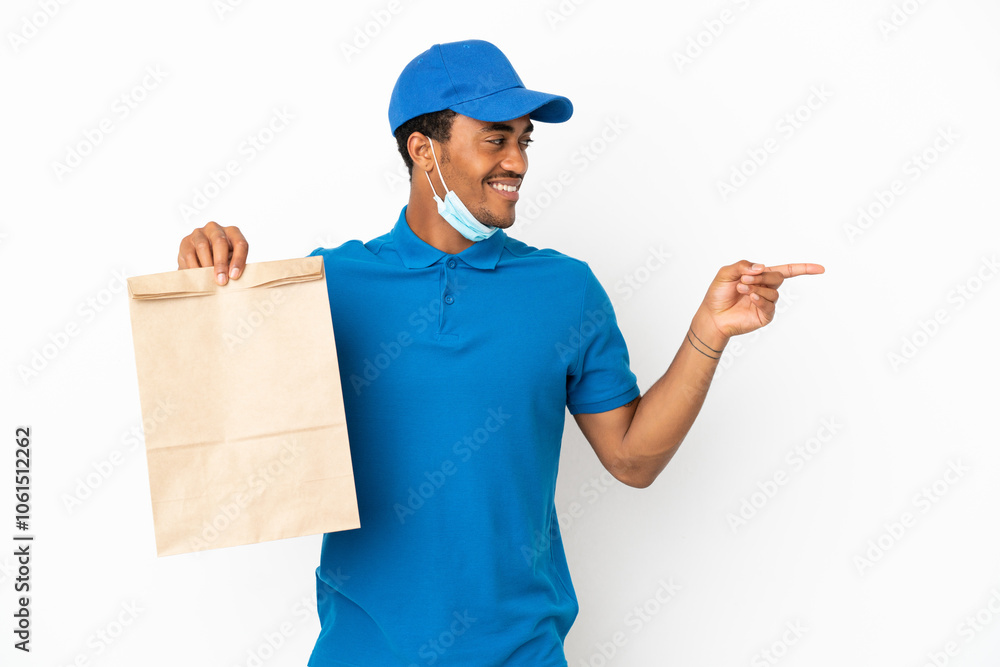 African American man taking a bag of takeaway food isolated on white background pointing finger to the side and presenting a product African American man taking a bag of takeaway food isolated on white background pointing finger to the side and presenting a product
