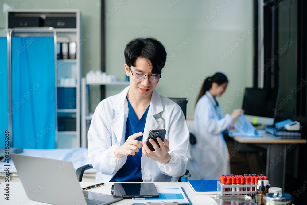 Confident young doctor in white medical uniform sit at desk working on computer. Smiling use laptop write Confident young doctor in white medical uniform sit at desk working on computer. Smiling use laptop write