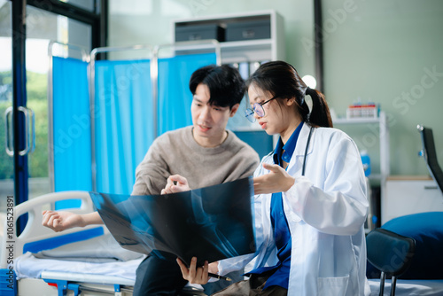 Asian doctor checks female patient's blood pressure in clinic.