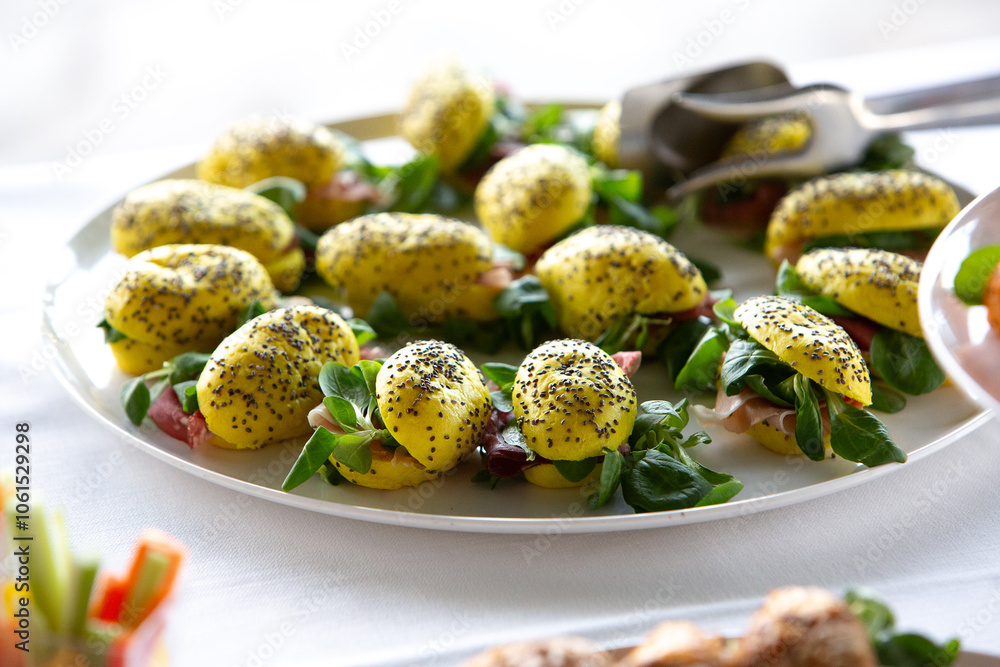 Yellow turmeric rolls with chia seeds, filled with ham and salad, served on a white plate during a buffet Yellow turmeric rolls with chia seeds, filled with ham and salad, served on a white plate during a buffet