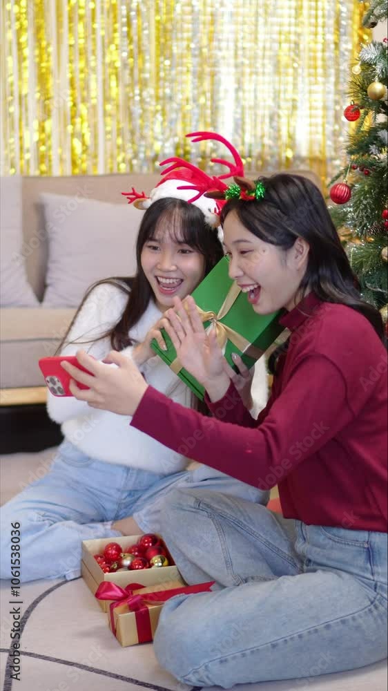 Two friends sit in front of a decorated Christmas tree, sharing a joyful video call. They are surrounded by wrapped presents, capturing the warmth and connection of the holiday. Two friends sit in front of a decorated Christmas tree, sharing a joyful video call. They are surrounded by wrapped presents, capturing the warmth and connection of the holiday.