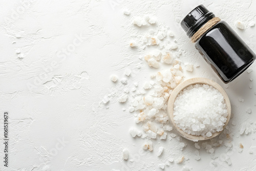 Bottle of salt next to wooden spoon with salt. photo