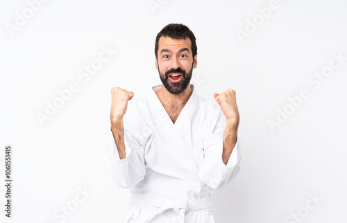 Young man doing karate over isolated white background celebrating a victory in winner position photo