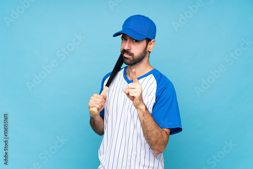Photography Young man playing baseball over isolated blue background frustrated and pointing