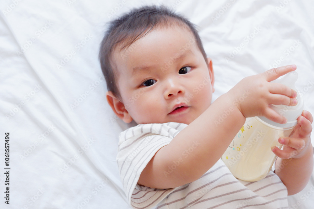 A cute little baby is sleeping and drinking milk on a white bed. A cute little baby is sleeping and drinking milk on a white bed.