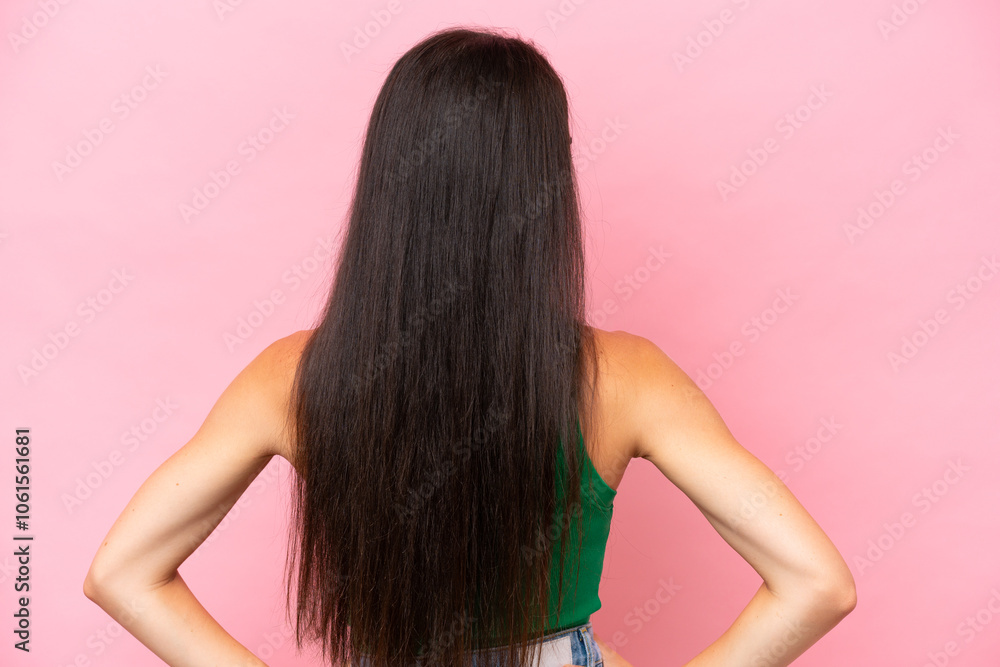 Young caucasian woman isolated on pink background in back position and looking side Young caucasian woman isolated on pink background in back position and looking side