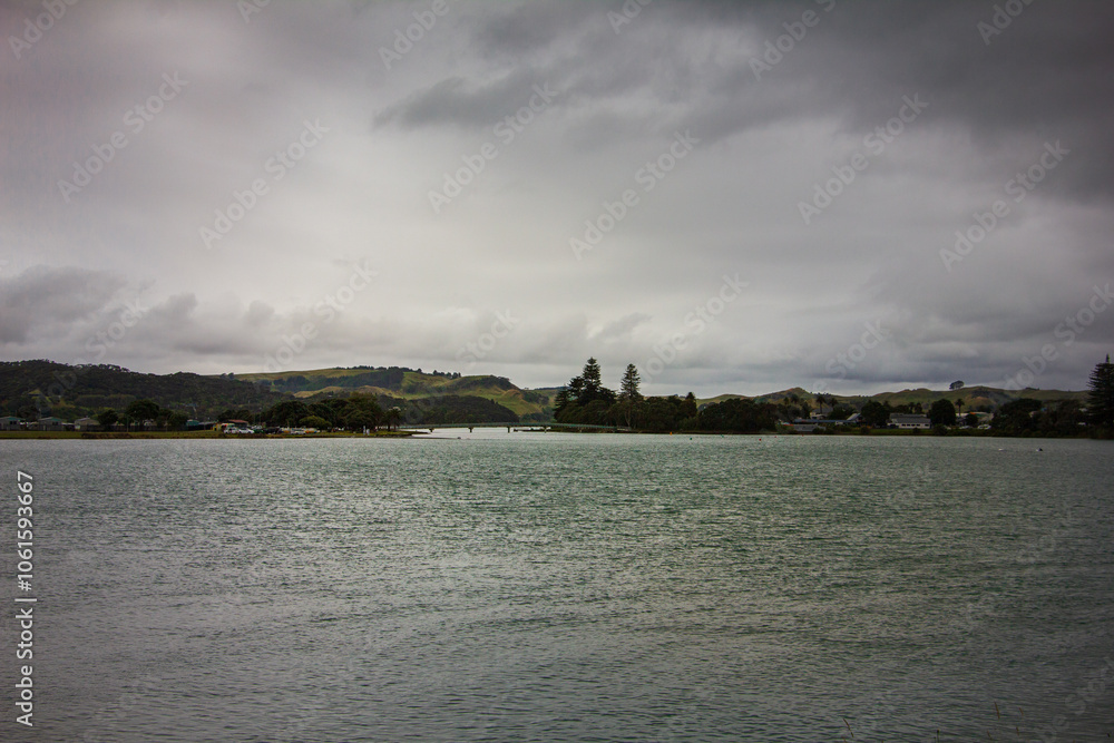Retro style photo of a breathtakingly serene view of the lake under beautiful, cloudy skies. Raglan, New Zealand. Toned image Retro style photo of a breathtakingly serene view of the lake under beautiful, cloudy skies. Raglan, New Zealand. Toned image