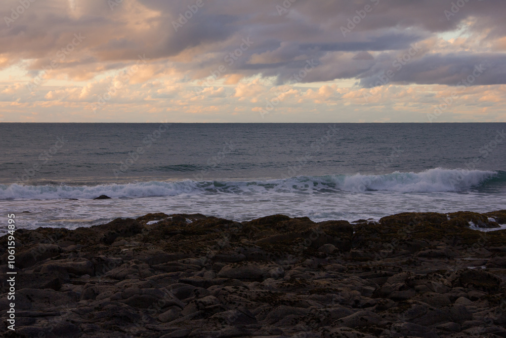 Waves crashing into coastal rocks at sunset. Dramatic sea coast background. Raglan, New Zealand Waves crashing into coastal rocks at sunset. Dramatic sea coast background. Raglan, New Zealand