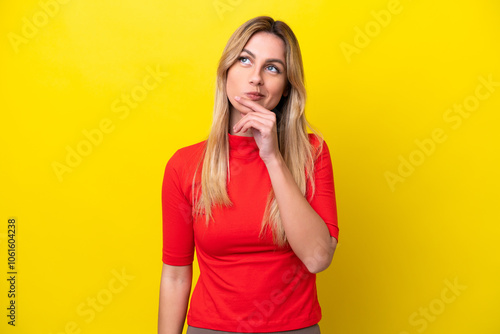 Young Uruguayan woman isolated on yellow background having doubts while looking up