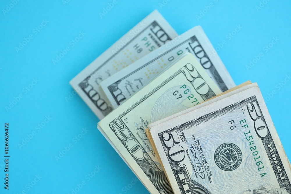 Big amount of hundred, fifty and twenty dollar bills in thick stack lies on bright blue color paper background Big amount of hundred, fifty and twenty dollar bills in thick stack lies on bright blue color paper background