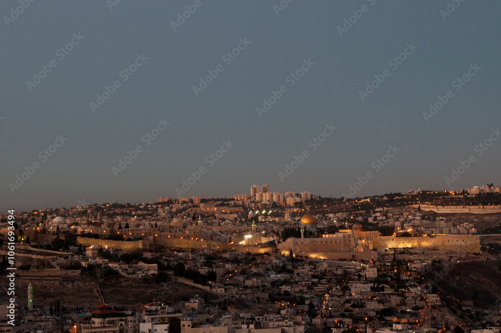 Fototapeta premium Panoramic view of the ancient walls of the Old City of Jerusalem with the golden Dome of the Rock shrine illuminated at twilight.