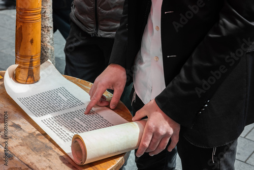 Closeup of a man's hands and fingers as he reads from the Scroll of Esther at an outdoor cafe on the Jewish holiday of Purim in Jerusalem, Israel. photo