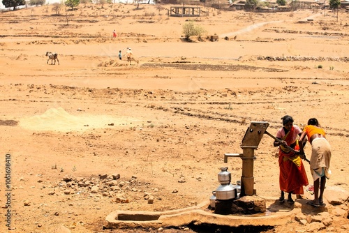 Foto Tribal woman pumping water from hand pump, India, Asia