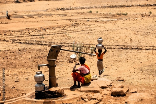 Tribal woman pumping water from hand pump, India